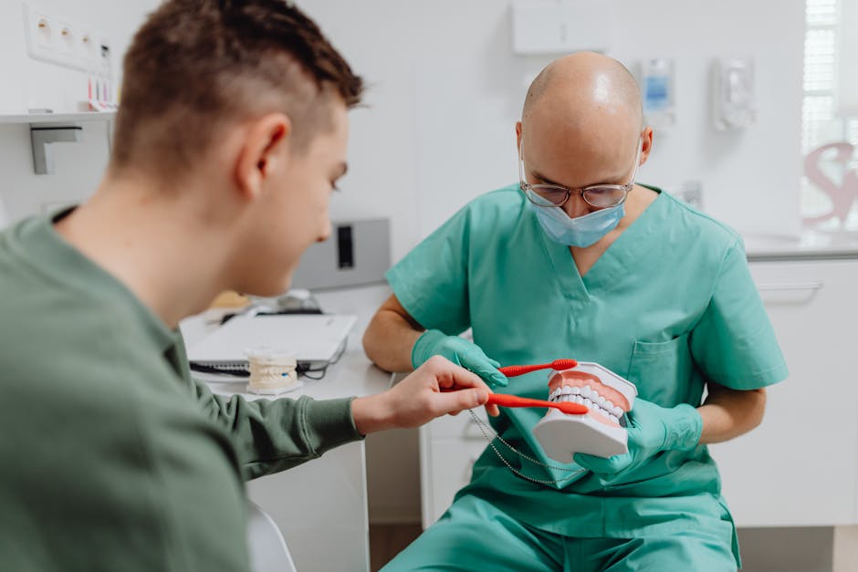 Zahnarzt erklärt einem Patienten an einem Zahnmodell die richtige Putztechnik – unterstützt durch Zahnarztsoftware in der Praxis.